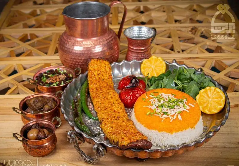 دیس مجلل کباب ایرانی با برنج زعفرانی، گوجه و فلفل کبابی، همراه با مخلفات سنتی در رستوران برکت، غذای اصیل و لذیذ.