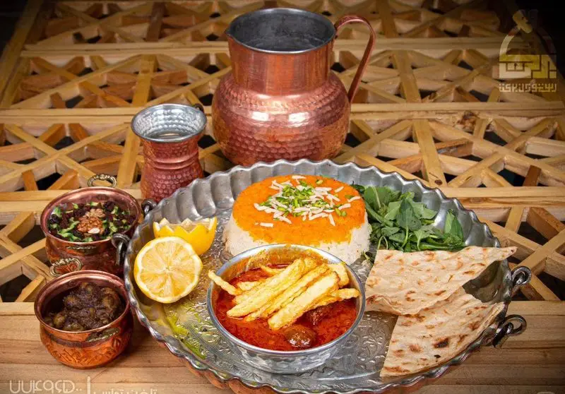 سفره سنتی رستوران برکت شامل چلو با تزئینات، خورش قیمه سیب‌زمینی، آبگوشت و خورشت ایرانی در سینی نقره‌ای.