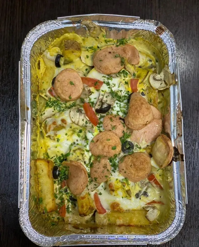 یک غذای فرنگی و رژیمی عالی از رستوران برکت، شامل املت یا گراتن با سوسیس، قارچ، زیتون، فلفل دلمه و جعفری، سرو شده در ظرف فویل مخصوص صبحانه.