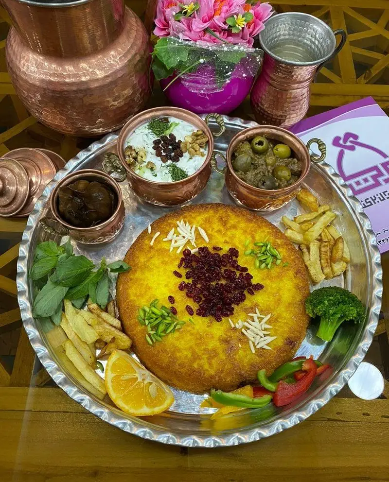 غذای سنتی ایرانی: ته چین زعفرانی مجلسی با زرشک و خلال پسته و بادام، ماست و خیار و انواع مخلفات در رستوران برکت.