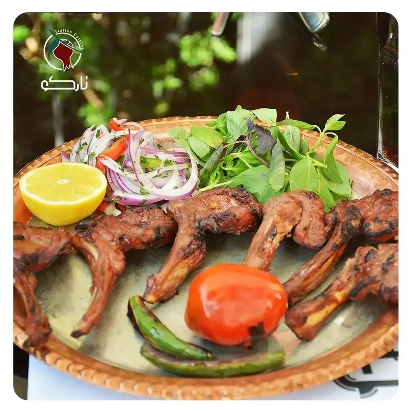 کباب دنده گوسفندی گریل شده در کافه رستوران نارکو با گارنیش پیاز، لیمو، گوجه و سبزیجات تازه، تجربه‌ای دلنشین.