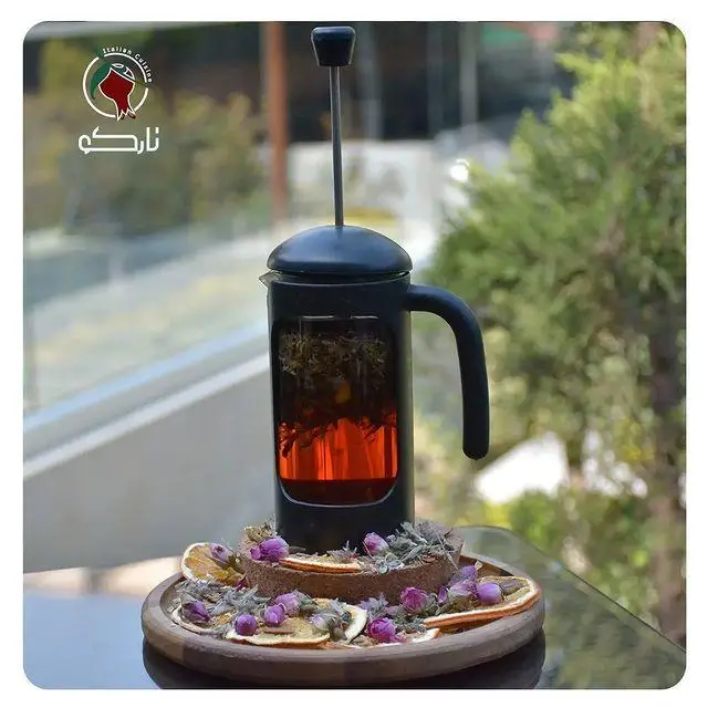 دمنوش گرم در فرنچ پرس و دسر خاص تزئین شده با گل و پرتقال خشک، تجربه‌ای دلنشین در کافه رستوران نارکو.