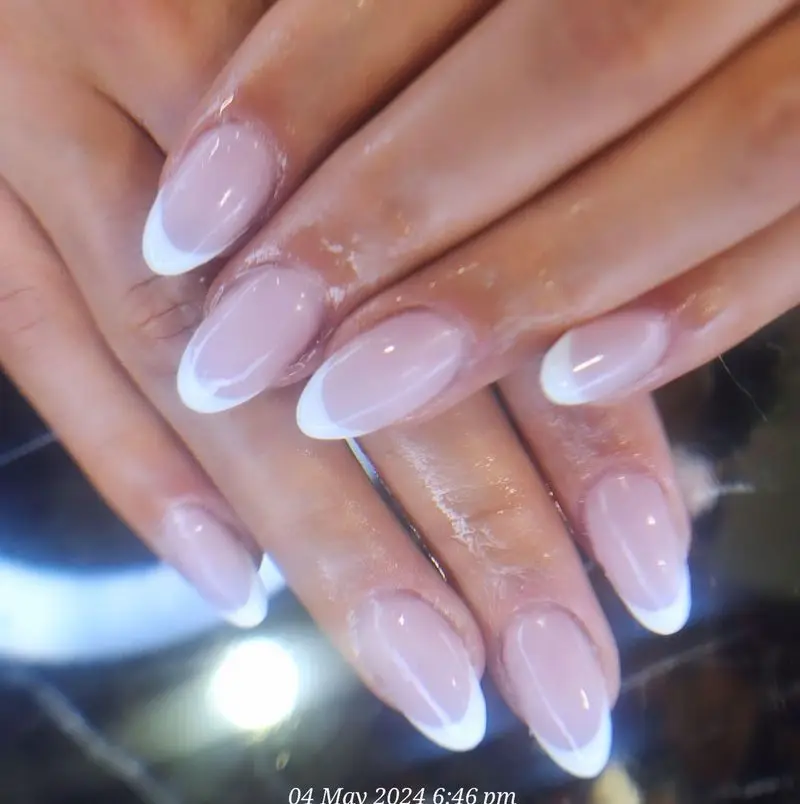 طراحی ناخن فرنچ کلاسیک و شیک روی ناخن‌های بیضی شکل با لاک ژل صورتی ملایم و لبه‌های سفید، مناسب برای استایل‌های رسمی و روزمره