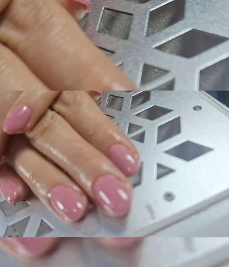 مدل کاشت و ژلیش ناخن دخترانه با لاک صورتی کالباسی براق و شیک روی صفحه فلزی مشبک دستگاه تهویه در سالن تخصصی زیبایی ناخن