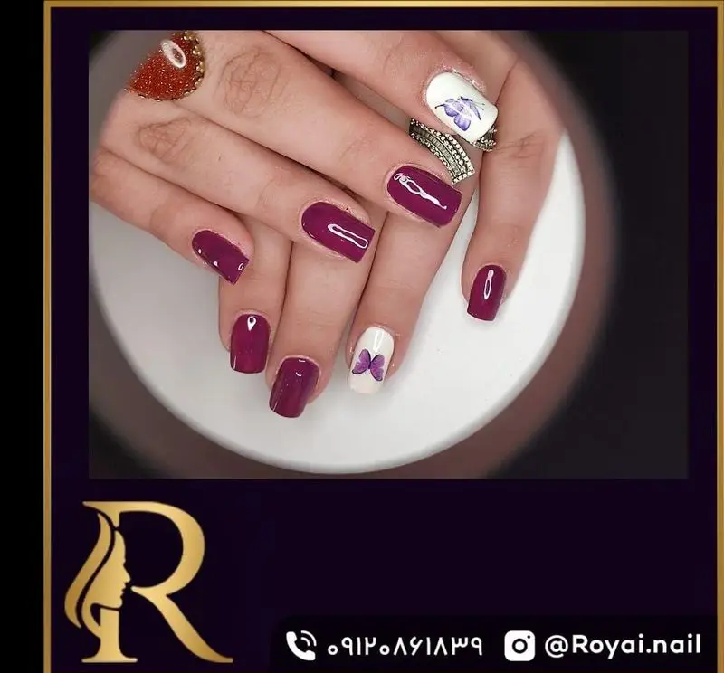 نمونه کاشت و طراحی ناخن با لاک بنفش بادمجانی براق و طرح پروانه روی لاک سفید در سالن زیبایی مدیس برای خانم‌ها