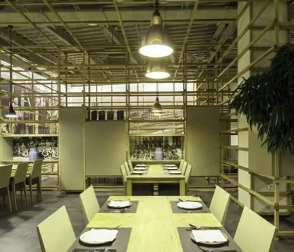 دکوراسیون داخلی مدرن و دلنشین کافی شاپ محفل با میز و صندلی چوبی، نورپردازی صنعتی و قفسه‌بندی خلاقانه برای فضای غذاخوری.