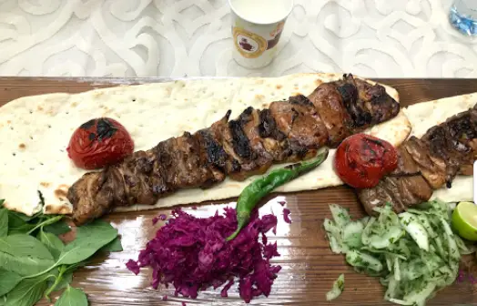 یک پرس کباب چنجه گوشت گوسفندی یا گوساله بر روی نان داغ، با گوجه کبابی، فلفل، کلم بنفش و مخلفات در رستوران هتل بلوط.