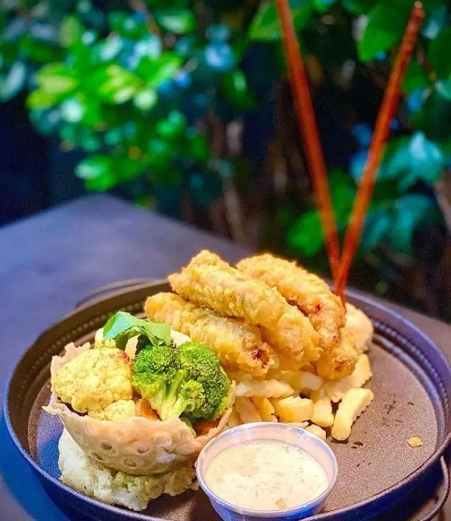 یک وعده غذایی اشتهاآور در کافه رستوران مازو، شامل فیله‌های ماهی سوخاری طلایی، سیب زمینی سرخ کرده و سبزیجات متنوع در کاسه‌ای خوراکی، به همراه سس مخصوص.