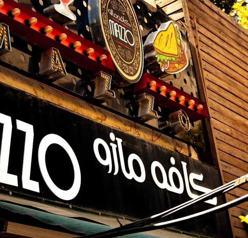 تابلوی برجسته کافه رستوران مازو با نورپردازی گرم، نمای بیرونی جذاب کسب و کار کافه و رستوران مازو را برای مشتریان به نمایش می‌گذارد.