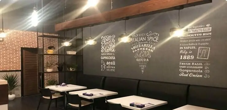 دکوراسیون داخلی مدرن و جذاب پیتزایی سیب360 با دیوارنویسی منوی پیتزا، میزهای سفید، نیمکت و نورپردازی شیک. محیطی دنج و عالی برای لذت از پیتزا.