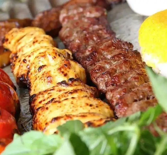 تصویری از سینی کباب میکس شامل کباب کوبیده و جوجه کباب طلایی. غذای سنتی ایرانی در باغ رستوران سایدا شهران با سبزی و لیمو تازه.