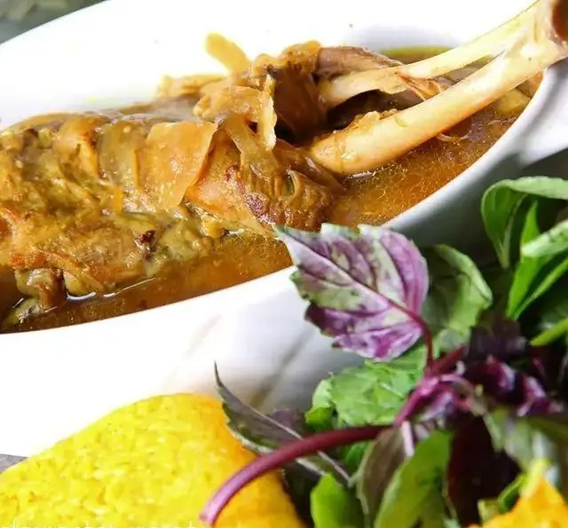 خوراک مرغ یا گوشت با سس غلیظ و برنج زردرنگ، تزئین شده با سبزیجات معطر، در باغ رستوران سایدا شهران. غذای دلچسب ایرانی.