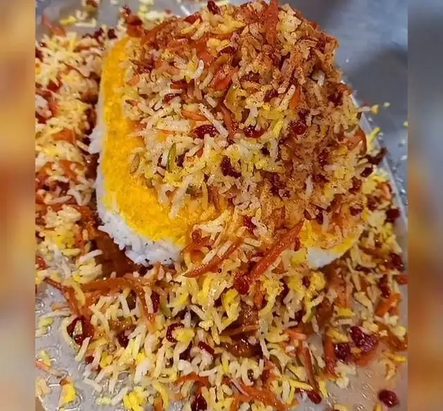 غذای سنتی و لذیذ ایرانی: مرصع پلو یا زرشک پلو مجلسی با برنج زعفرانی، خلال هویج، زرشک و پسته در باغ رستوران سایدا شهران.