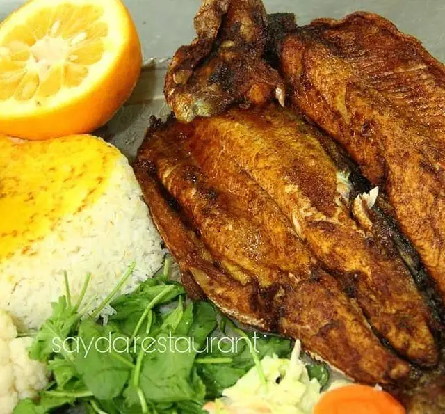 غذای خوشمزه باغ رستوران سایدا شهران: ماهی سرخ شده با برنج زعفرانی، پرتقال و سبزیجات تازه. تجربه‌ای بی‌نظیر از غذای دریایی.