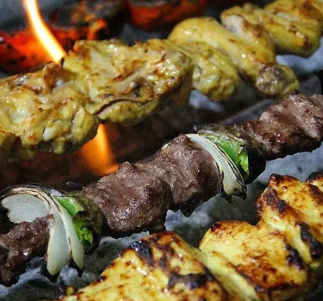 جوجه کباب و کباب چنجه گوشت تازه، با پیاز و فلفل سبز، در حال پخت روی حرارت ذغال و آتش در باغ رستوران سایدا شهران.