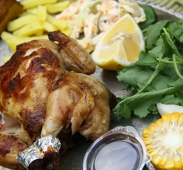 بشقاب غذای اصلی مرغ بریان طلایی با سیب‌زمینی سرخ‌کرده، سالاد کلم، برش لیمو، سبزیجات تازه و ذرت، از منوی باغ رستوران سایدا شهران.