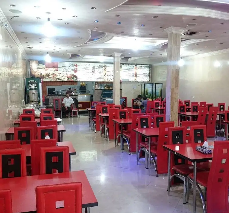 فضای داخلی دنج و مدرن پیتزا پرشین با میز و صندلی‌های قرمز شیک، آماده پذیرایی از مشتریان عزیز در محیطی دلنشین و روشن.