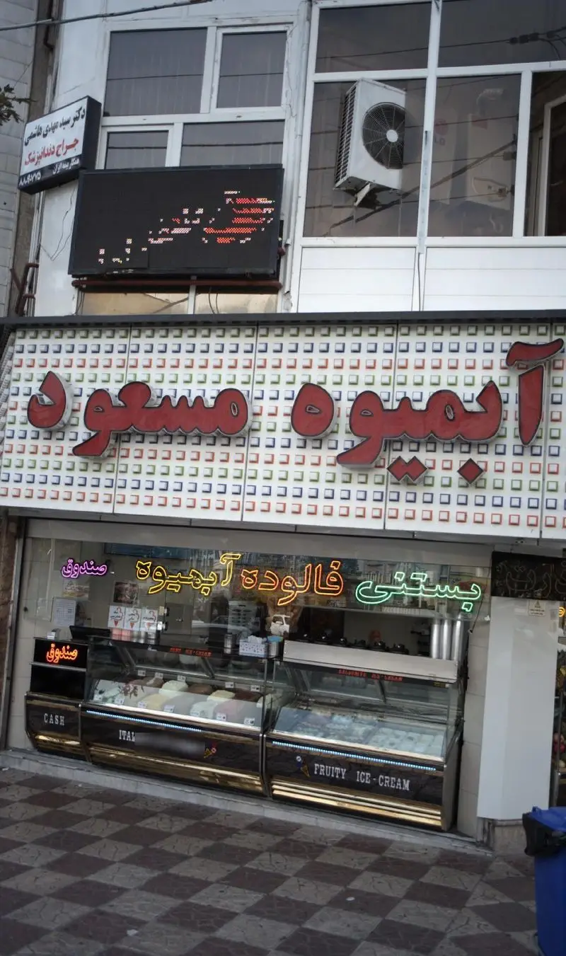 فروشگاه ویتامینه، آبمیوه، بستنی و فالوده مسعود. ویترین‌های جذاب محصولات یخی و نوشیدنی‌های سرد با تابلوهای نئونی درخشان.