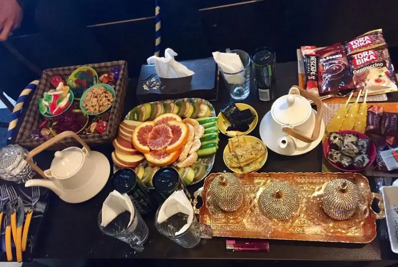 پذیرایی کامل کافه مافه: میز پر از میوه‌های تازه، شیرینی، آجیل، چای، قهوه و دسر برای دورهمی‌های دلنشین.