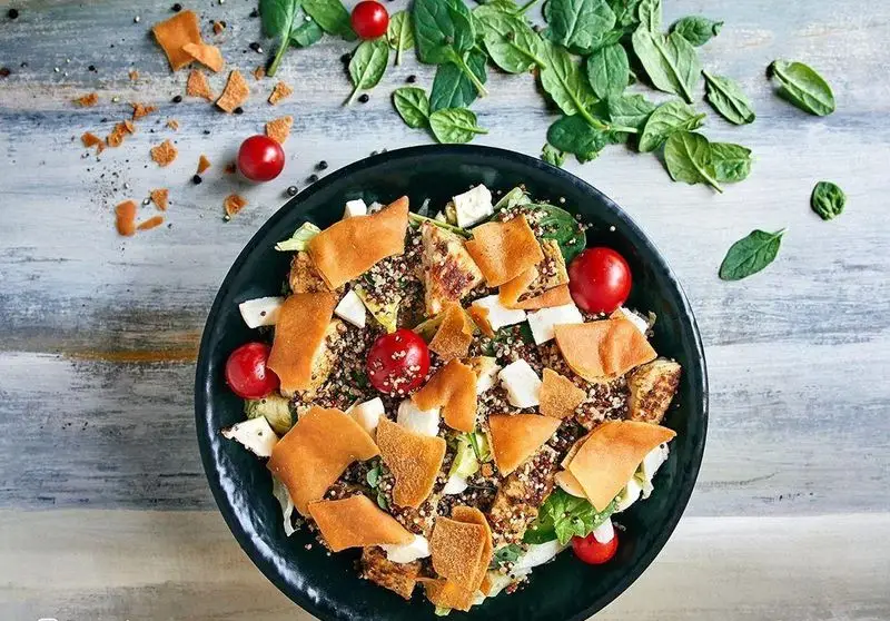 سالاد کینوآ و سبزیجات تازه باروژ با گوجه گیلاسی، پنیر فتا و تکه‌های نان سوخاری، گزینه‌ای سالم از فست فود باروژ.