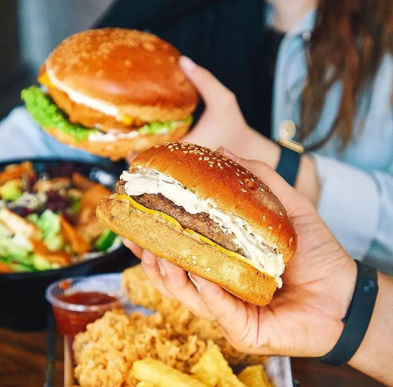 تصویر نزدیک از مشتریان فست فود باروژ که در حال لذت بردن از برگرهای محبوب، مرغ سوخاری ترد، سیب زمینی سرخ کرده و سالاد تازه هستند.