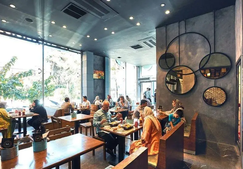 فضای داخلی دنج و مدرن فست فود باروژ، با مشتریان در حال تجربه غذاهای خوشمزه و نمایی دلنشین از بیرون.