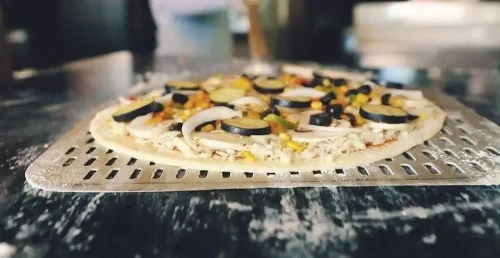 پیتزای تازه و پر سبزیجات فست فود باروژ روی سینی پخت با قارچ، زیتون، ذرت و کدو. آماده برای طعم یک تجربه خاص.