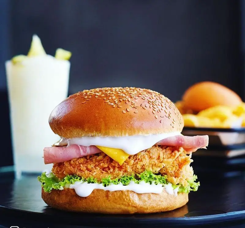 همبرگر مرغ سوخاری لذیذ فست فود باروژ با نان کنجدی، ژامبون، پنیر، کاهو و سس، همراه با نوشیدنی و سیب زمینی سرخ کرده.
