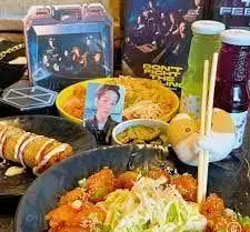 نمایی از میز رستوران کره ای سُوان با انواع غذاهای لذیذ و محبوب کره ای، شامل نودل، رول سرخ شده، نوشیدنی و دکوراسیون چشم نواز.