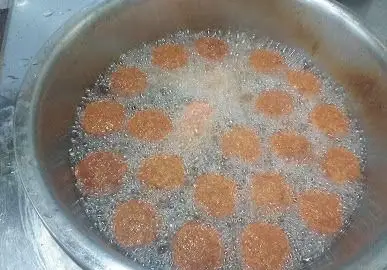 تصویری از آماده سازی وسوسه‌انگیز غذاهای سرخ‌شده در فست فود پاتوق. سرخ شدن فلافل‌های ترد و تازه در روغن داغ.