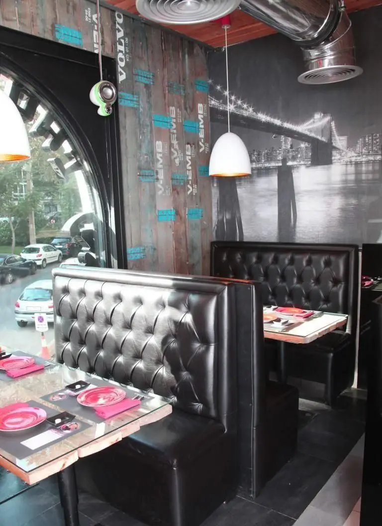 فضای داخلی رستوران چاپ چاپ (فرشته)، با طراحی مدرن شامل مبلمان چرمی مشکی، میزهای شیشه‌ای و دیوارهای دکوراتیو با طرح شهری.