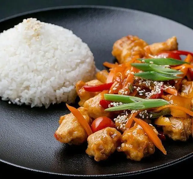 غذای چینی: مرغ سوخاری ترد با سس شیرین و ترش، هویج، فلفل دلمه، گوجه و پیازچه، همراه با پلو سفید کنجدی از رستوران چاپ چاپ فرشته.