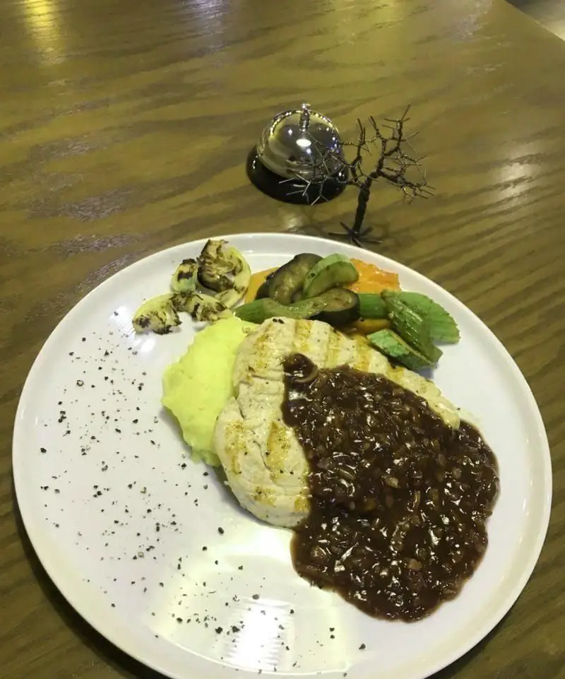 نمای نزدیک از سینه مرغ گریل شده با پوره سیب زمینی، سبزیجات تازه و سس مخصوص در کافی شاپ ریو وو. وعده‌ای سالم و خوشمزه برای ناهار یا شام.