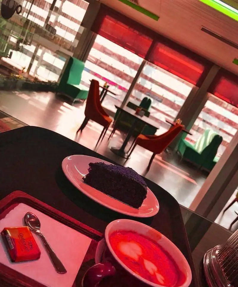 نمایی جذاب از فضای داخلی کافی شاپ ریو وو: کیک شکلاتی، لاته آرت با قلبی و شکلات روی میز. مکانی دنج برای قهوه و دسر.