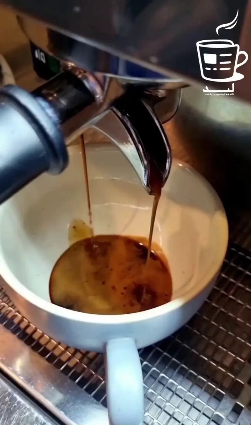 تصویری از عصاره‌گیری قهوه اسپرسو دو شات از دستگاه حرفه‌ای در کافه لید، با کرمای غنی و رنگ زیبای قهوه در فنجان آماده سرو.
