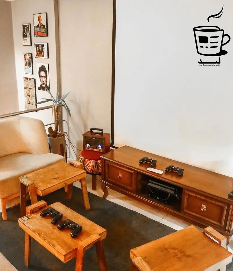 فضای داخلی کافه لید: ترکیبی دلنشین از منطقه بازی پلی استیشن، نمایش فیلم، دکور چوبی و مبل راحتی برای جمع‌های دوستانه و نوشیدن قهوه.