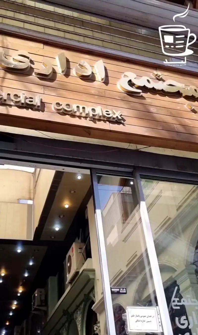 نمای ورودی مجتمع تجاری اداری با تابلوی طلایی Commercial complex و درب‌های شیشه‌ای، کسب‌وکار کافه لید