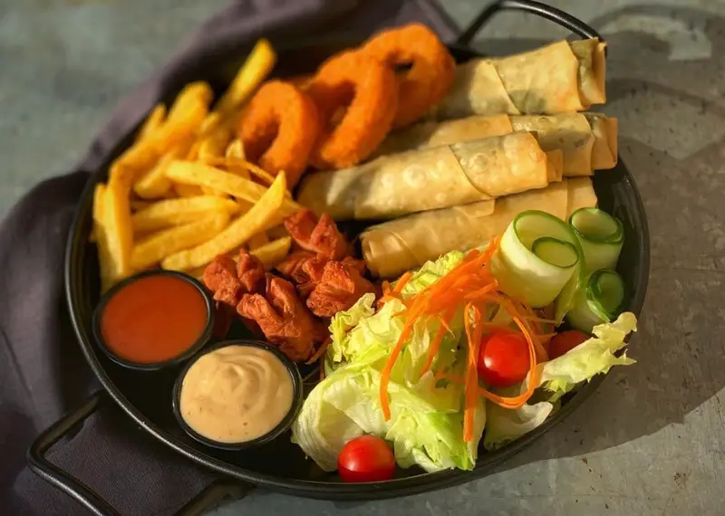 یک سینی کامل فست فود شامل سیب زمینی سرخ کرده، پیاز سوخاری، رول‌های سرخ شده، سوسیس و دو سس دیپ به همراه سالاد تازه از کافه لِبنان.