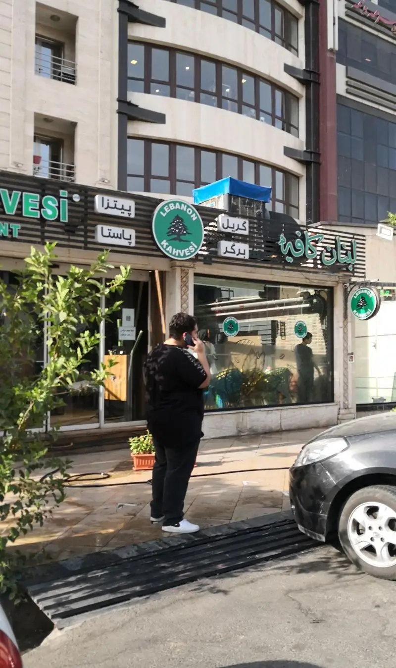 نمای بیرونی کافه و رستوران لبنان کافه (Lebanon Kahvesi) با لوگوی درخت سرو، منوی پیتزا، پاستا، گریل و برگر در یک روز آفتابی در شهر.