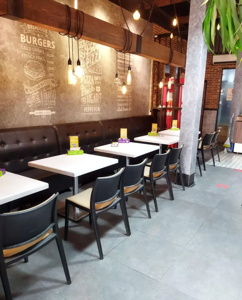 فضای داخلی دنج و مدرن رستوران پیتزا سیب ۳۶۰ با دیوارهای گرافیتی، میز و صندلی راحت و نورپردازی جذاب برای صرف پیتزا و برگر.