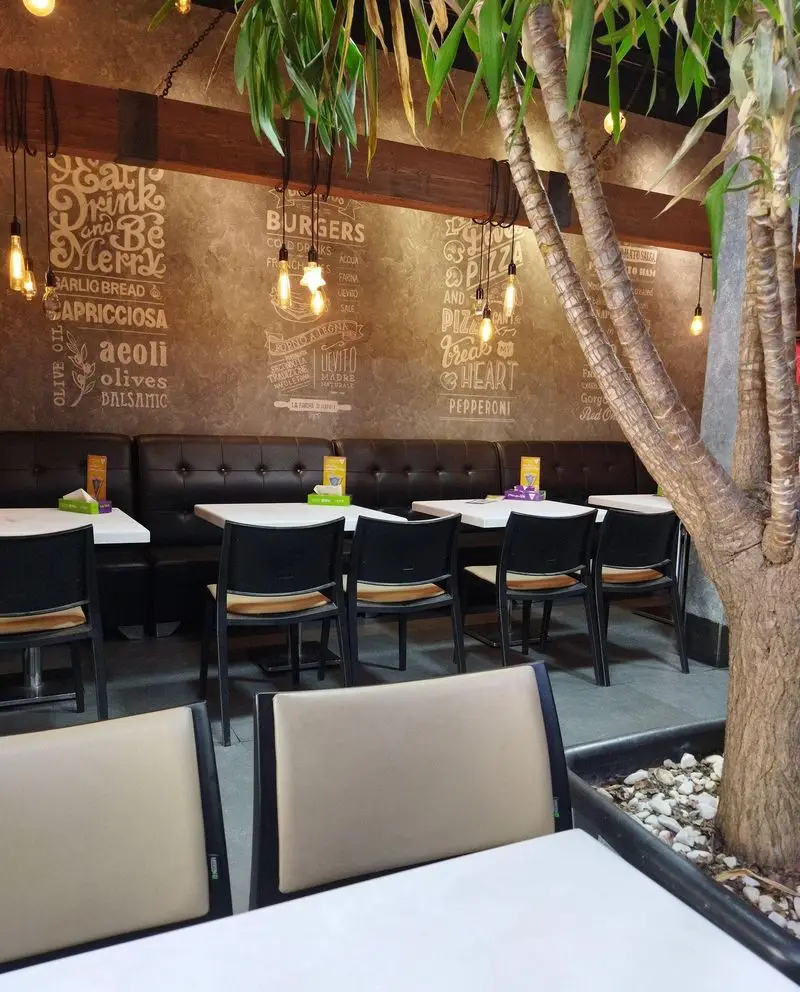 فضای داخلی جذاب پیتزا سیب ۳۶۰ با دکوراسیون منوی دیواری و نورپردازی ادیسونی، میز و صندلی راحت و محیطی دلنشین.