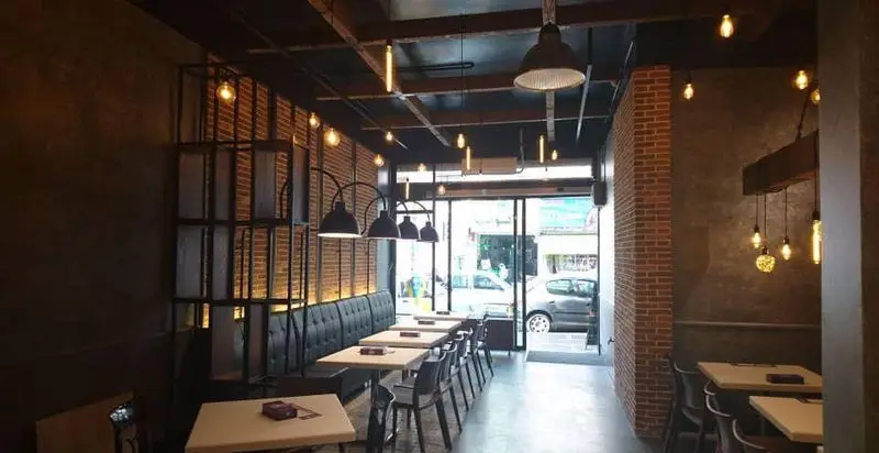 دکوراسیون داخلی شیک و مدرن رستوران پیتزا سیب ۳۶۰ با دیوارهای آجری، نورپردازی صنعتی و فضایی دلنشین برای مشتریان.