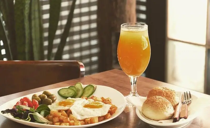 یک صبحانه لذیذ و دلپذیر از پیتزا الوند شامل دو تخم مرغ نیمرو بر روی سیب زمینی نگینی، همراه با زیتون، گوجه، خیار و سبزیجات تازه، نان گرم و آب پرتقال طبیعی.