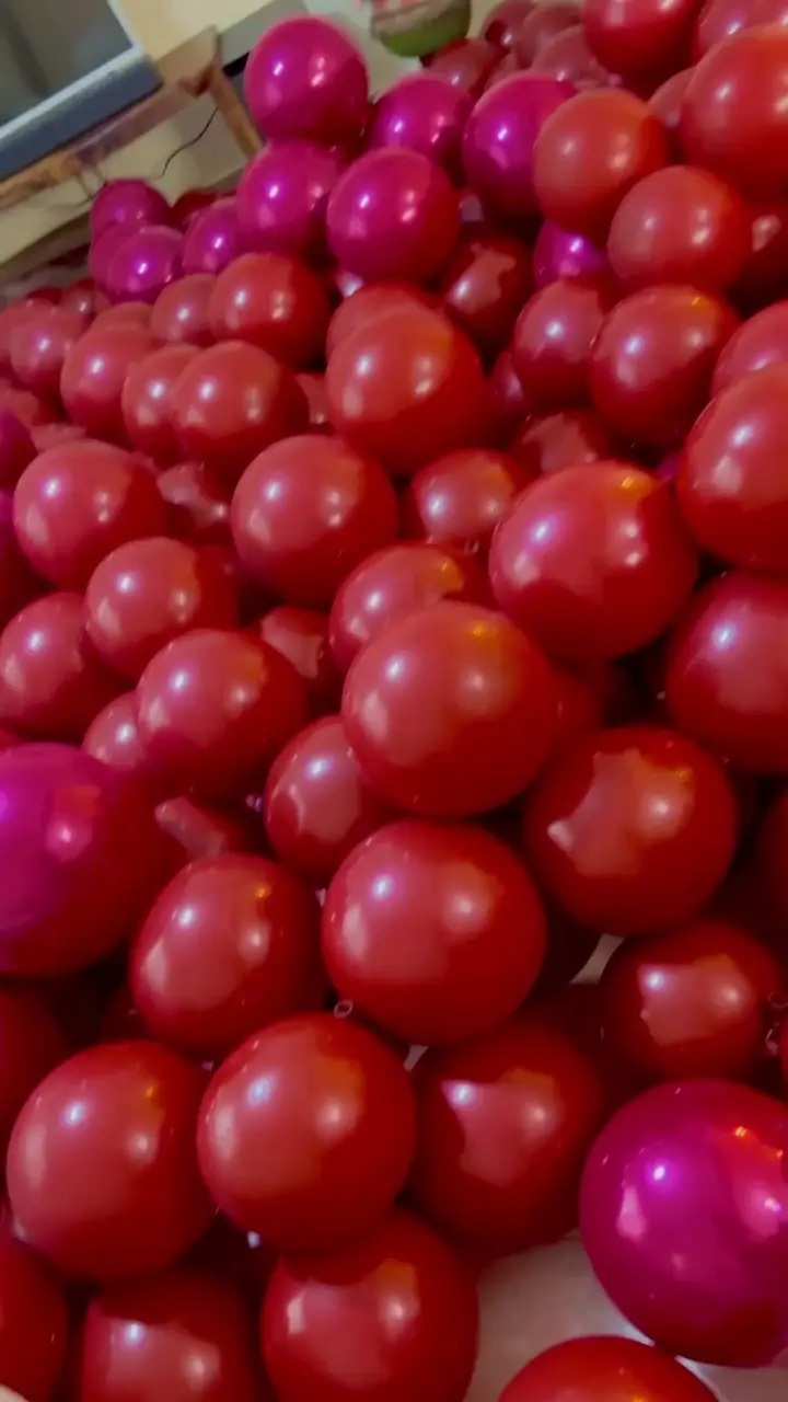 تصویری انبوه و دلنشین از بادکنک‌های قرمز، زرشکی و سرخابی براق، مناسب بادکنک‌آرایی و دیزاین حرفه‌ای جشن‌ها از بالونیا.