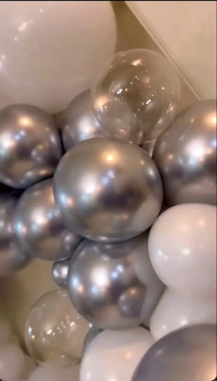 تصویر نزدیک از دیزاین بادکنک‌های کروم نقره‌ای، سفید و شفاف در یک آرایش زیبا. بالون آرایی شیک و جذاب برای جشن تولد و مهمانی‌های خاص.