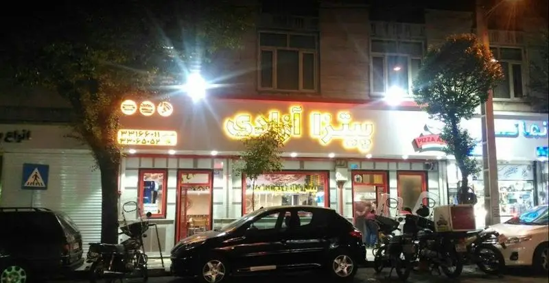 نمایی جذاب در شب از پیتزا آزادی، فست فودی مدرن با تابلو روشن و شماره‌های تماس ۳۳۱۶۶۰۱۱ و ۳۳۰۶۵۰۵۲ جهت سفارش انواع پیتزا و ساندویچ.