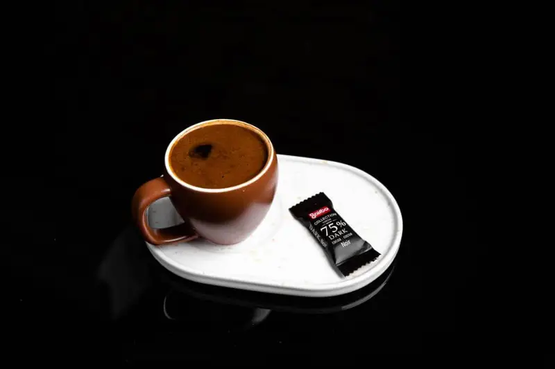 لذت نوشیدن قهوه تلخ و داغ در فنجان زیبای قهوه ای همراه با شکلات دارک گلدو ۷۵ درصد، تجربه ای بی نظیر در کافه گریل ببک.