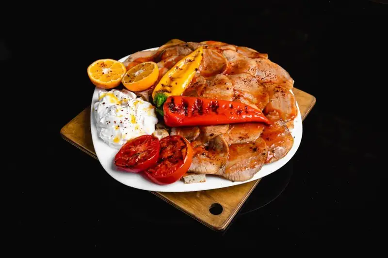 بشقاب شاهانه کباب گوشت گریل شده با فلفل و گوجه کبابی، سس ماست و پرتقال در کافه گریل ببک. لذت طعم اصیل.