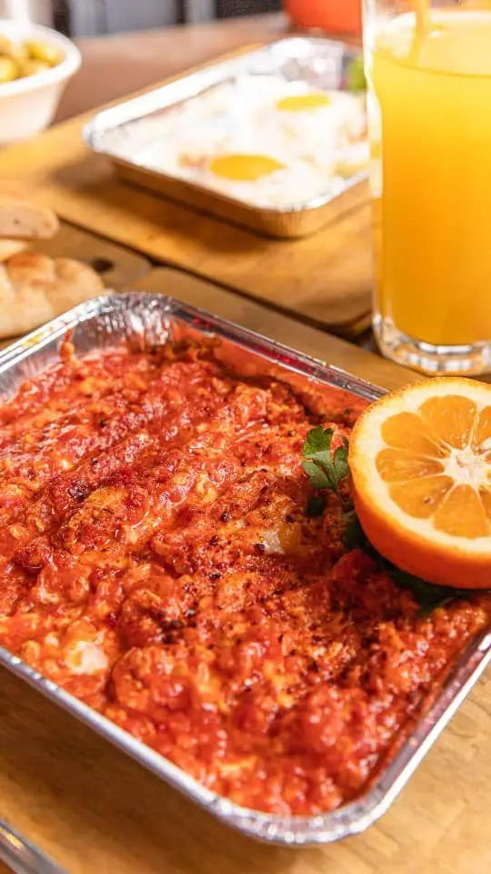 میز صبحانه کافه گریل ببک شامل املت گوجه و تخم مرغ در فویل، به همراه آب پرتقال تازه و نان برای یک شروع دلپذیر.