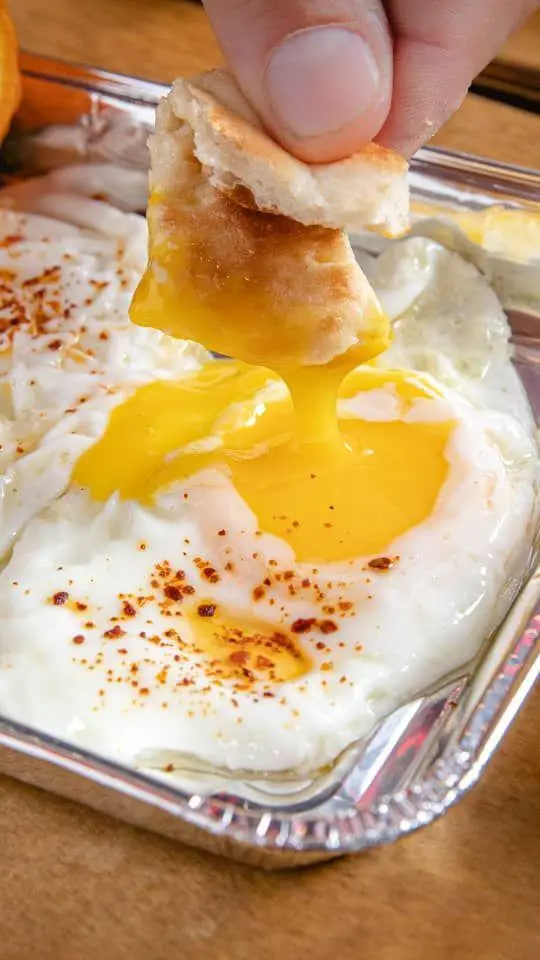 صبحانه دلپذیر کافه گریل ببک: نان در زرده عسلی تخم مرغ های نیمرو شده با ادویه قرمز در ظرف فویلی.